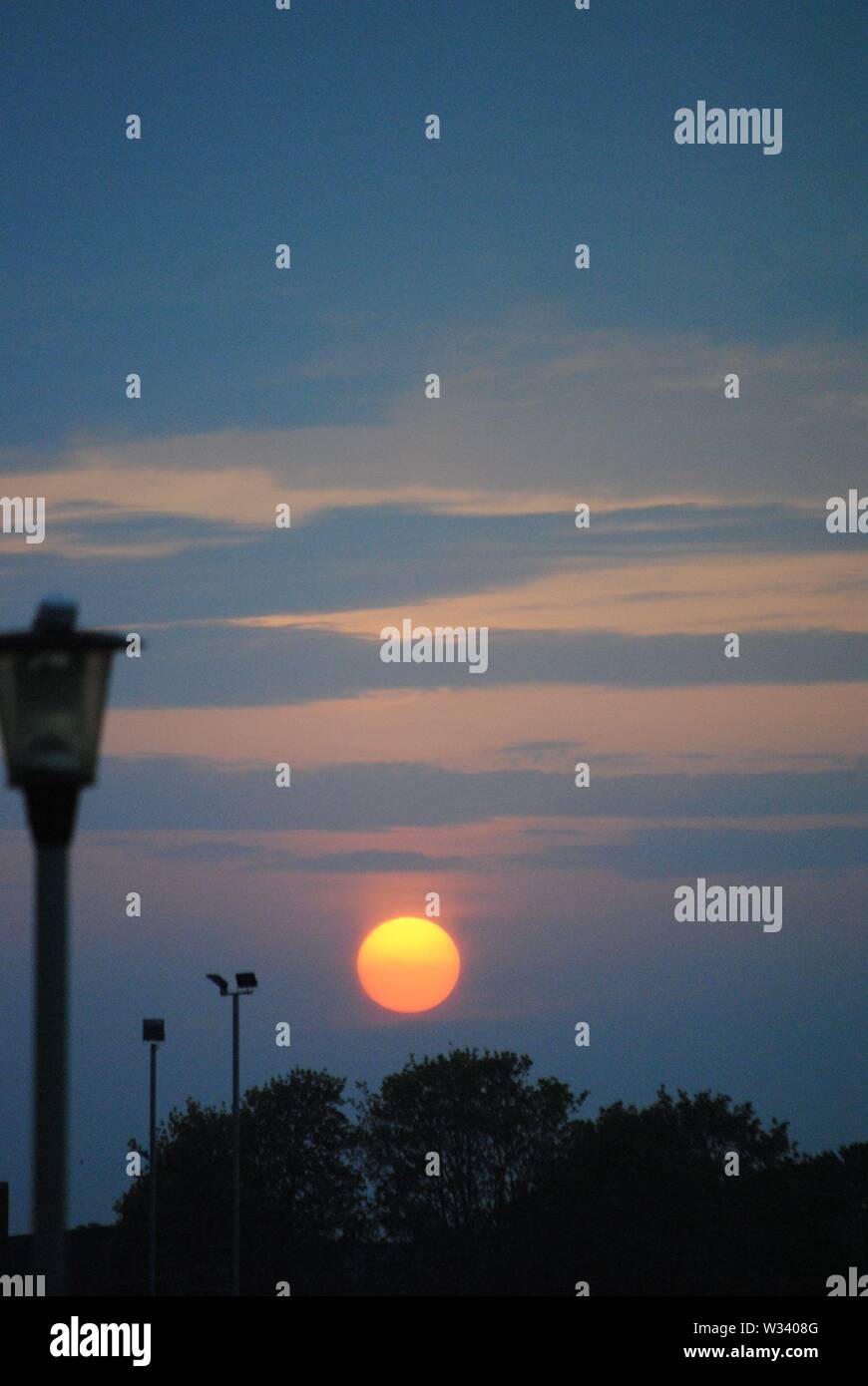 Gold orb of the stting sun low on the Horizon  with pastel colours in the sky Stock Photo