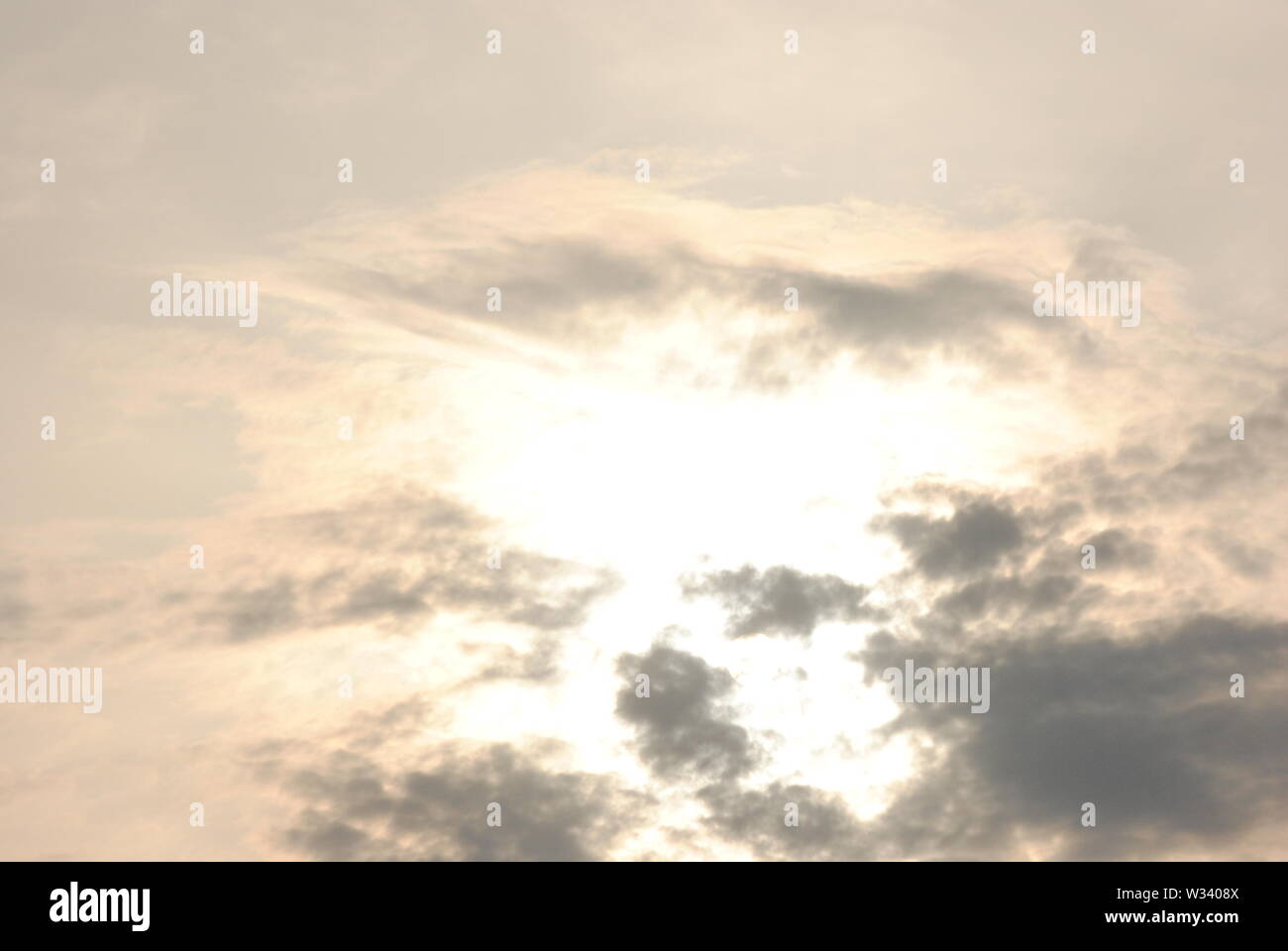 Hazy diffuse sun shining behind  grey clouds in a fuzzy  abstract sky Stock Photo