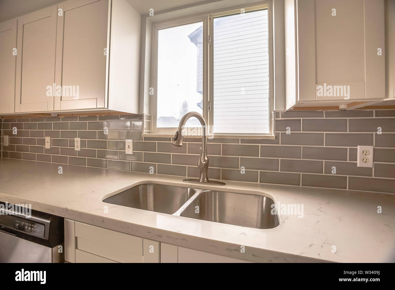 Double Bowl Stainless Steel Sink Against Tiled Wall With Window