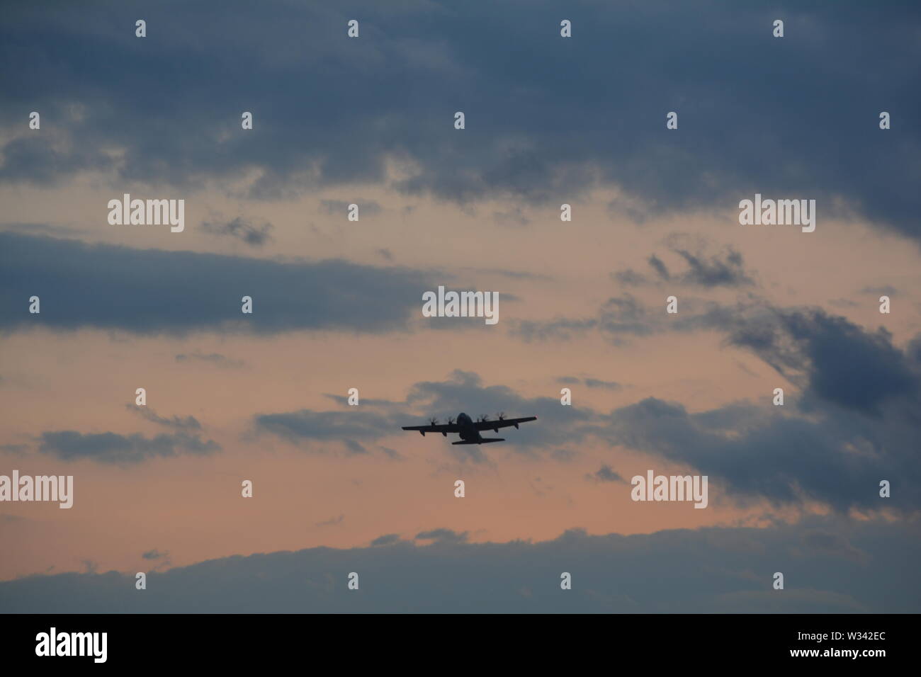 Evening clouds with awsome light and a Hercules  airplane,  flying Pat's. Stock Photo