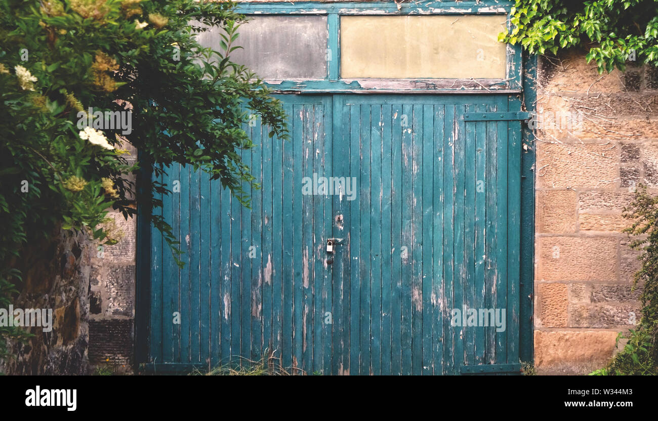 An old wooden garage door made of planks that are severely weathered Stock Photo