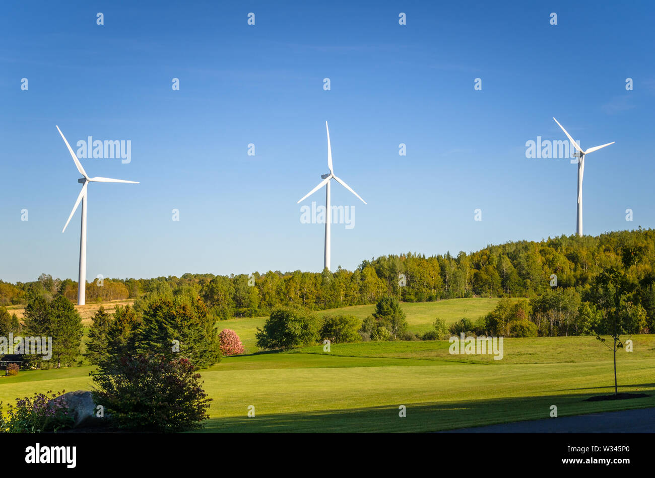 Wind turbines in a rolling rural landscape and blue sky. Renewable energy. Stock Photo