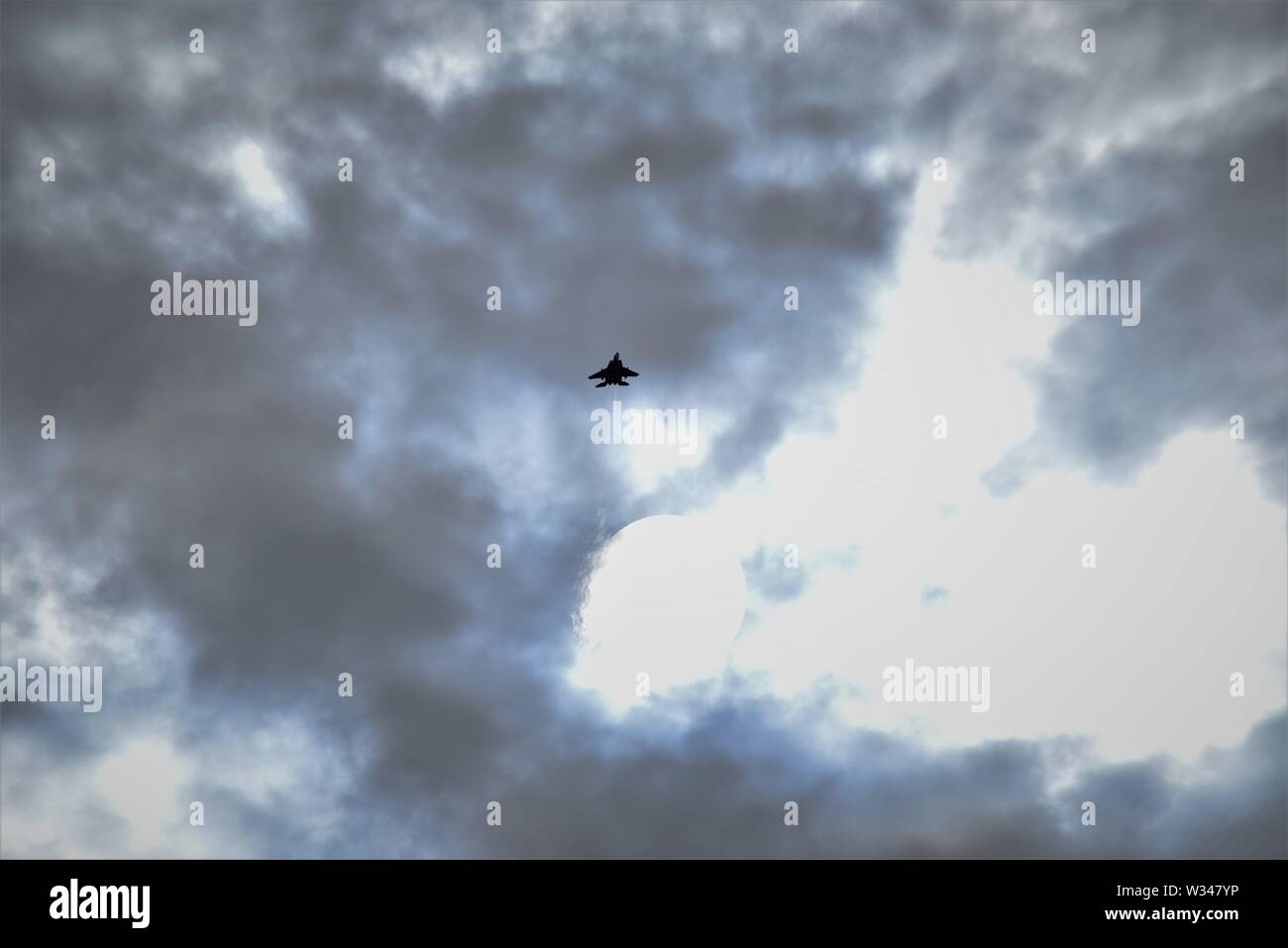 F 15 jet fighter in the distance climbing into a dark grey cloudy sky ...