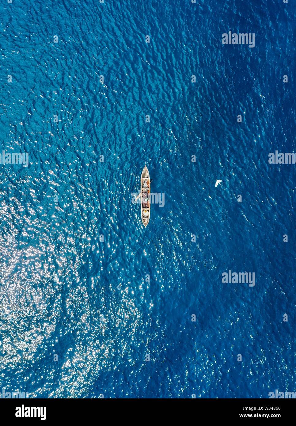 Boat fishing in the deep blue ocean from above Stock Photo