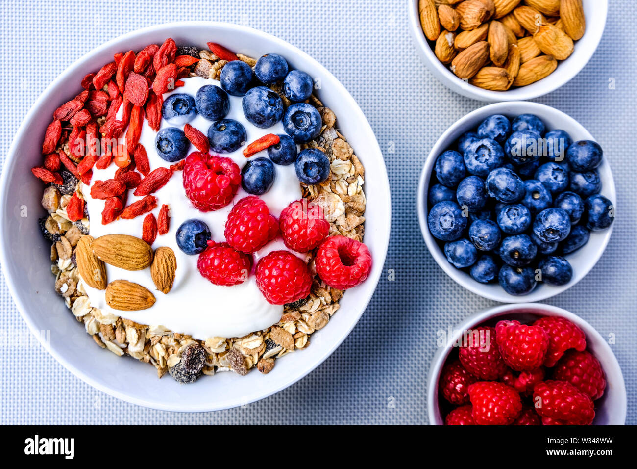 Healthy Vegetarian Breakfast Bowl of Muesli With Fresh Fruit Nuts and Yogurt in White Bowls Stock Photo