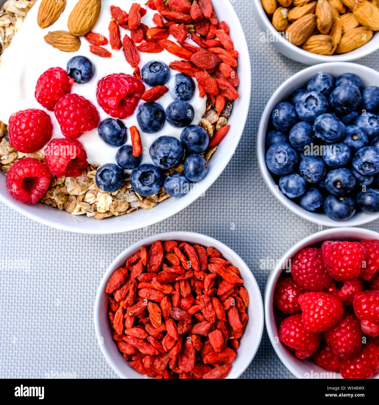 Healthy Vegetarian Breakfast Bowl of Muesli With Fresh Fruit Nuts and Yogurt in White Bowls Stock Photo