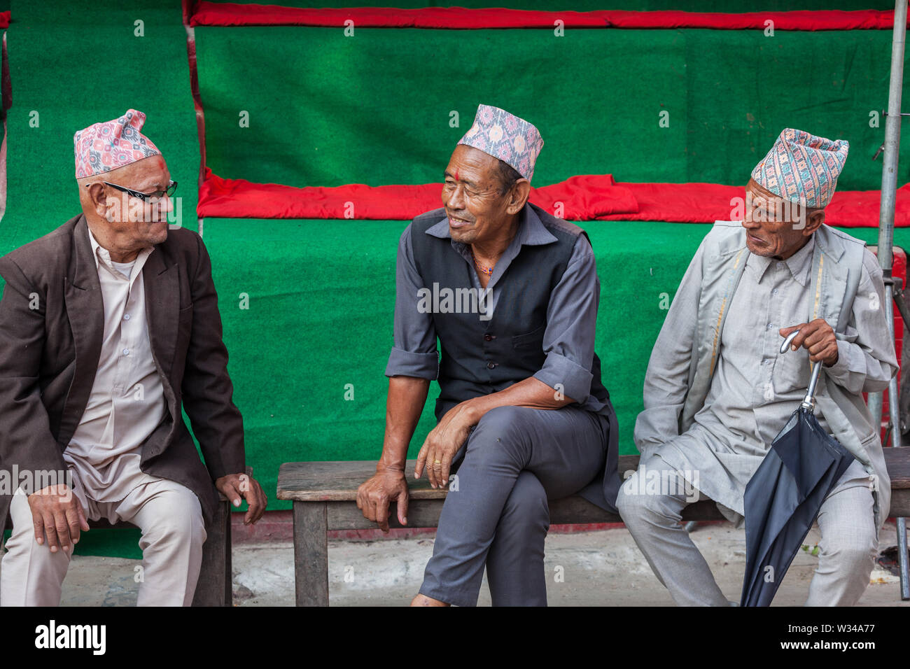 Three Nepalese men sat talking in Kathmandu Stock Photo