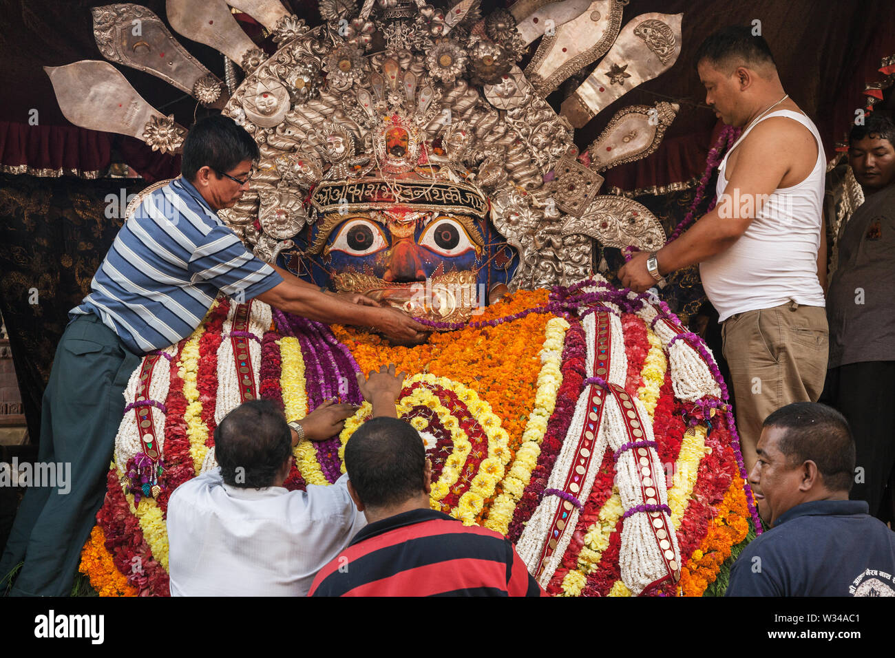 Decorating a symbolic god with flowers and garlands in Kathmandu Stock Photo