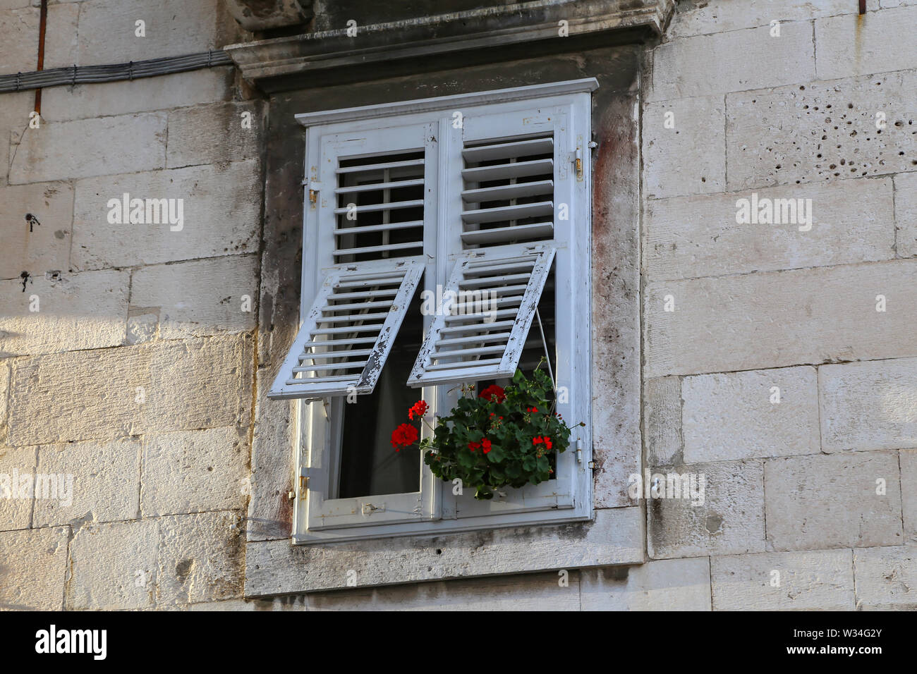 The windows of the house with shutters and flowers Stock Photo