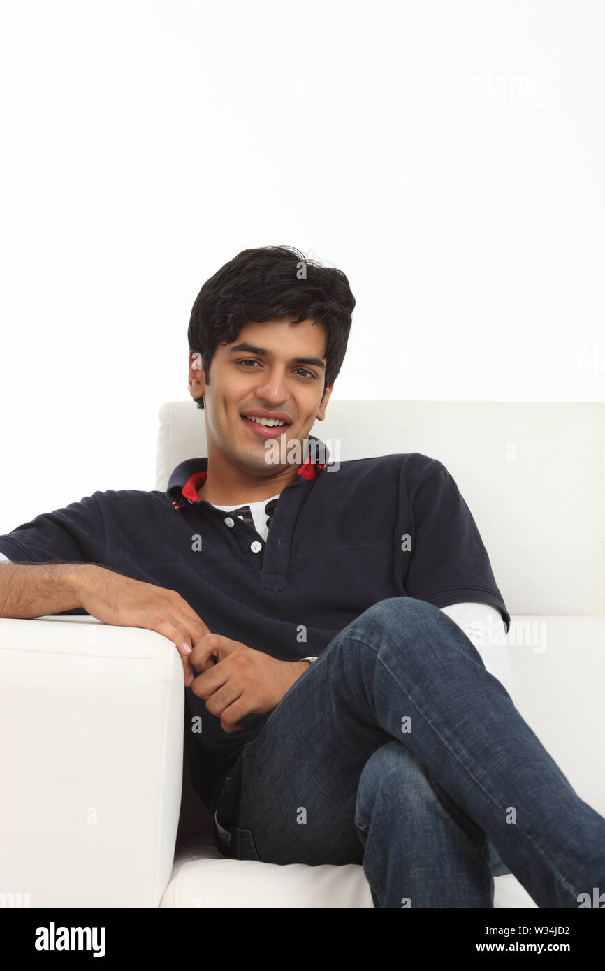 Portrait of an Indian young man sitting on couch Stock Photo - Alamy