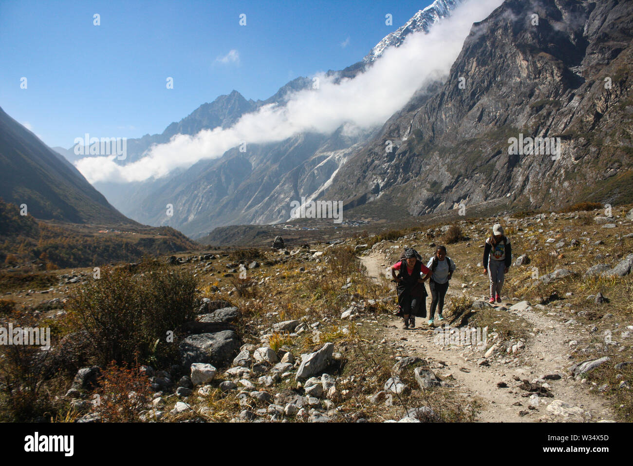 Local people walking up-to Langtang Valley through the mountains and stone-paved way. Hard life but peaceful and happy life. Stock Photo