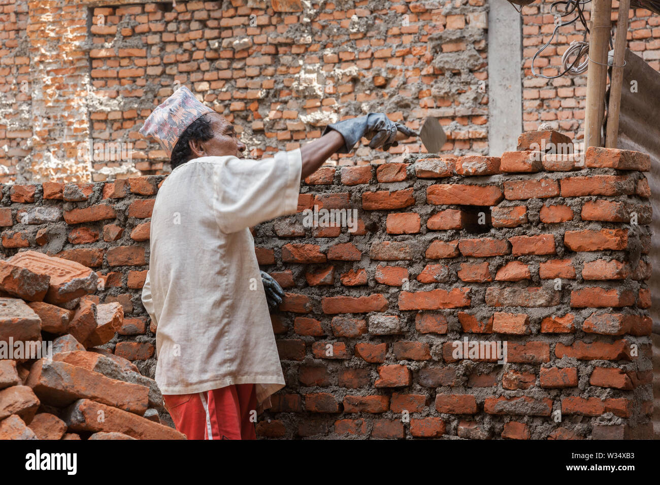 Man rebuilding the wall of a building after an earthquake in Kathmandu Stock Photo
