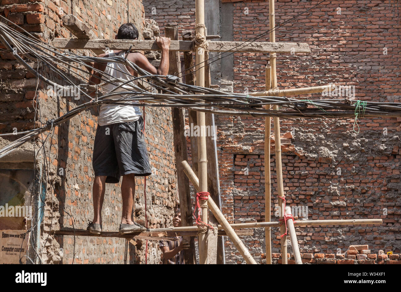 Man standing on bamboo scaffolding during reconstruction after earthquake damage in Kathmandu. Stock Photo