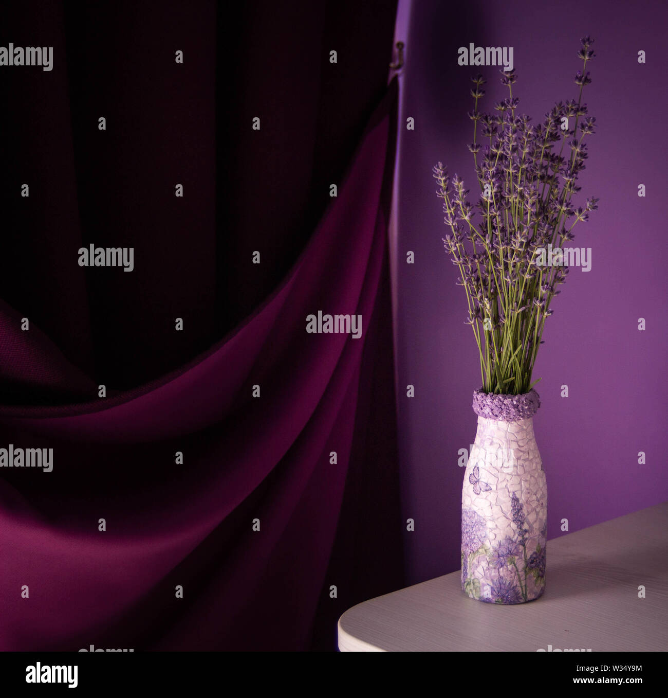 Lavender in the vase  on the table. Purple curtain and violet wall background. Stock Photo