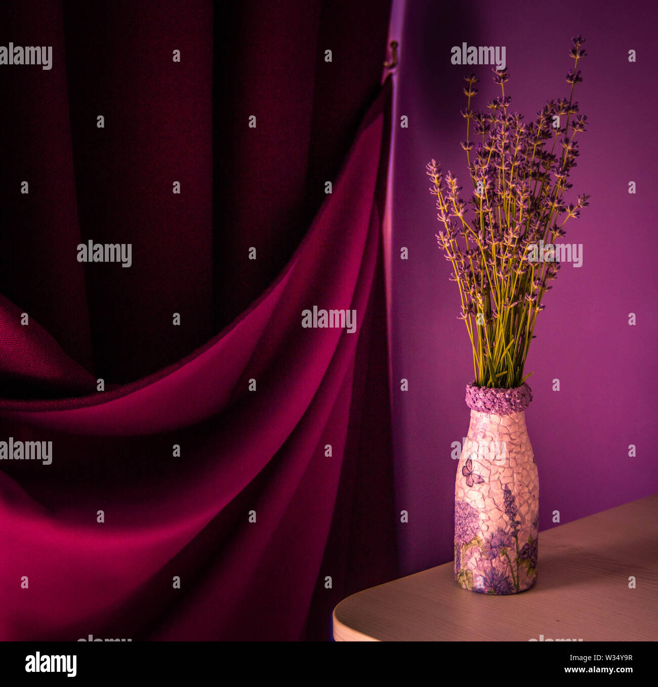 Lavender in the vase  on the table. Purple curtain and violet wall background. Stock Photo