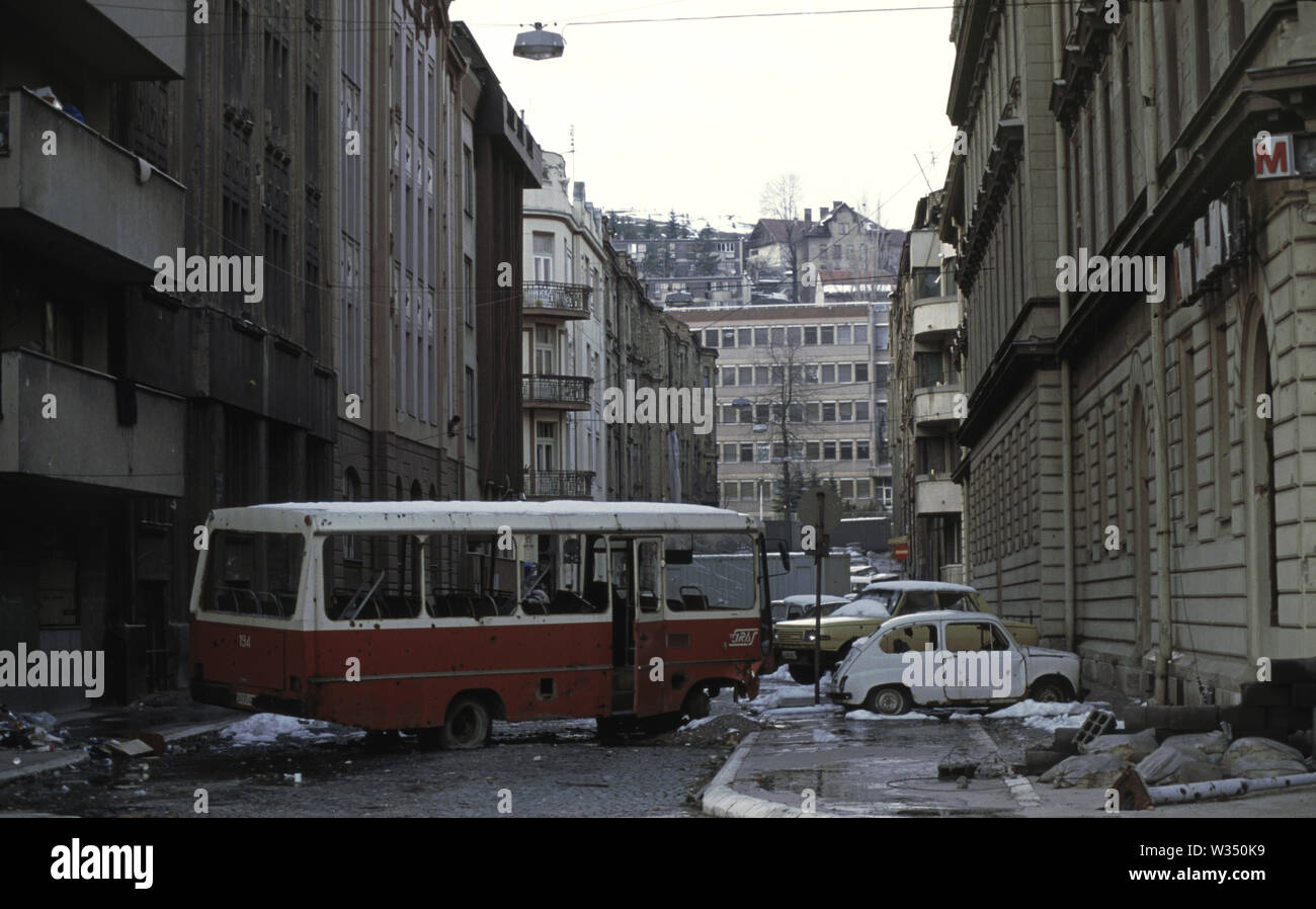 2nd April 1993 During the Siege of Sarajevo: the view north along Kralja Tvrtka street. A wrecked bus acts as cover from Bosnian Serb snipers who are just a few hundred metres to the south. At the bottom of the street is the west wing of the Dr Abdulah Nakas General Hospital, known locally as the 'City' or 'French' Hospital during the war. Stock Photo