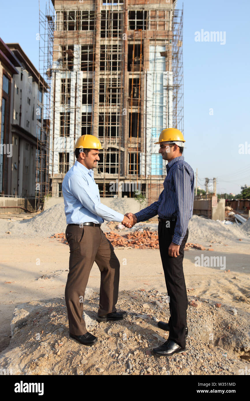 Two engineers shaking hands at a construction site Stock Photo