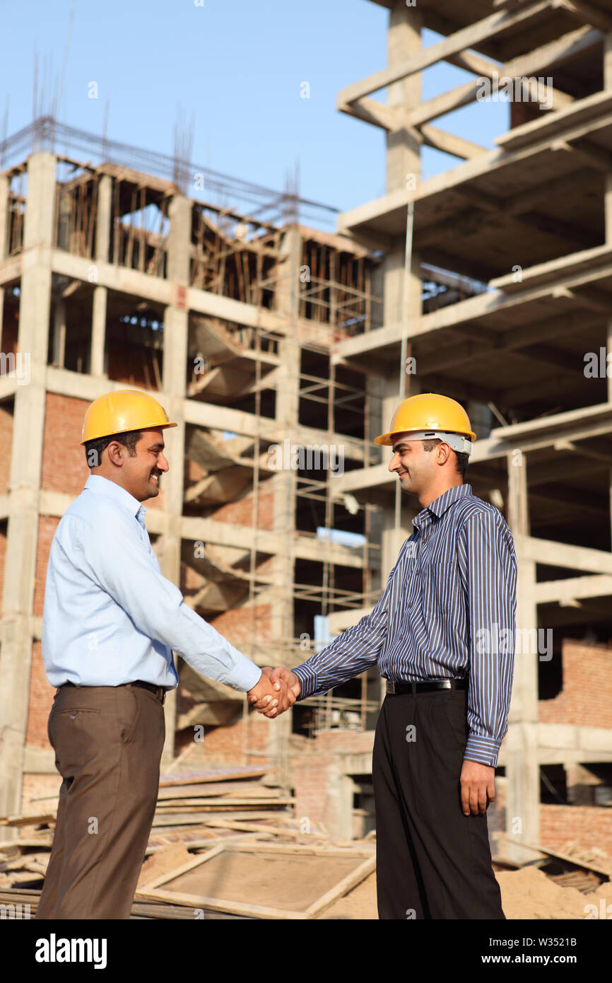 Two engineers shaking hands at a construction site Stock Photo