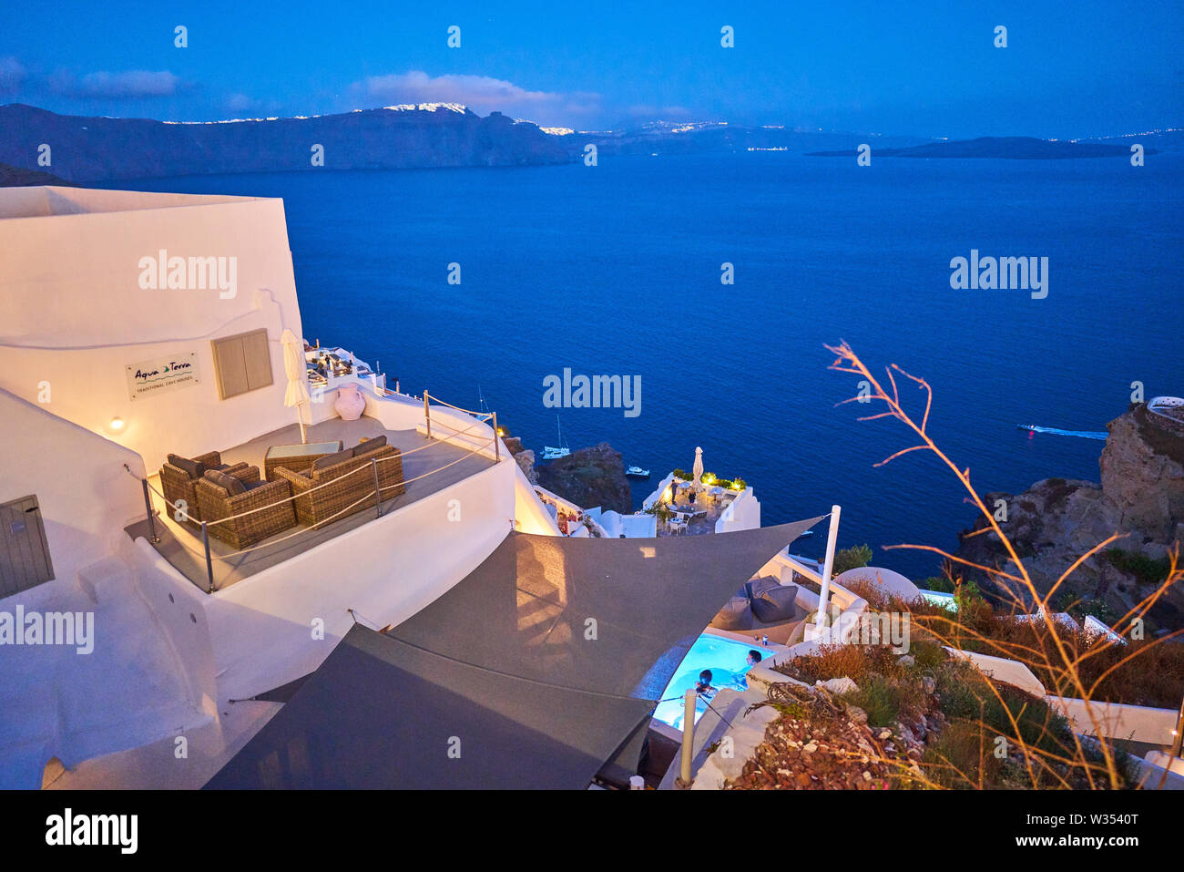 Tourists in luxury restaurants and on Oia Castle wait for the sunset with Caldera View and the famous Windmill in Oia, Santorini , Greece at 04 June 2 Stock Photo