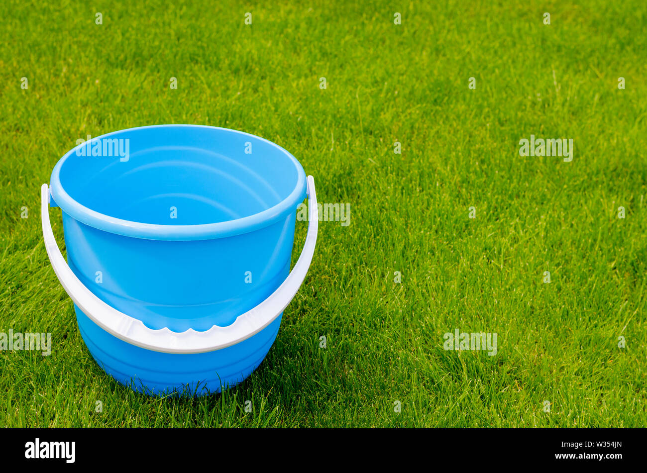 Colored plastic garden buckets on background of green grass. Studio
