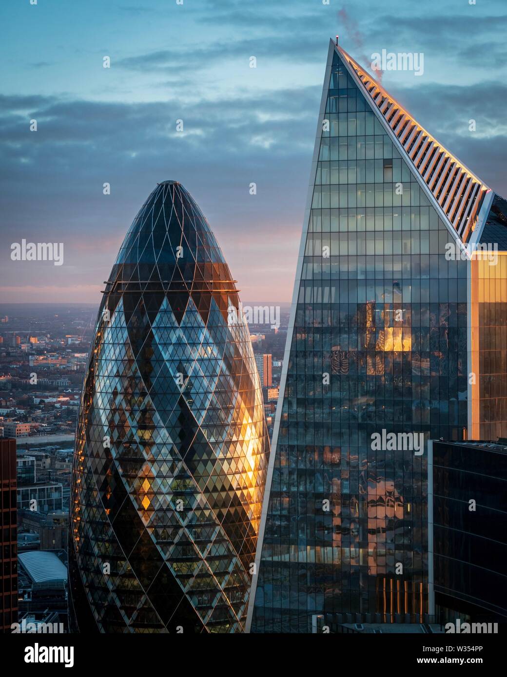 The golden rays of sunrise hitting the side of the Gherkin and Scalpel buildings in the city of London Stock Photo