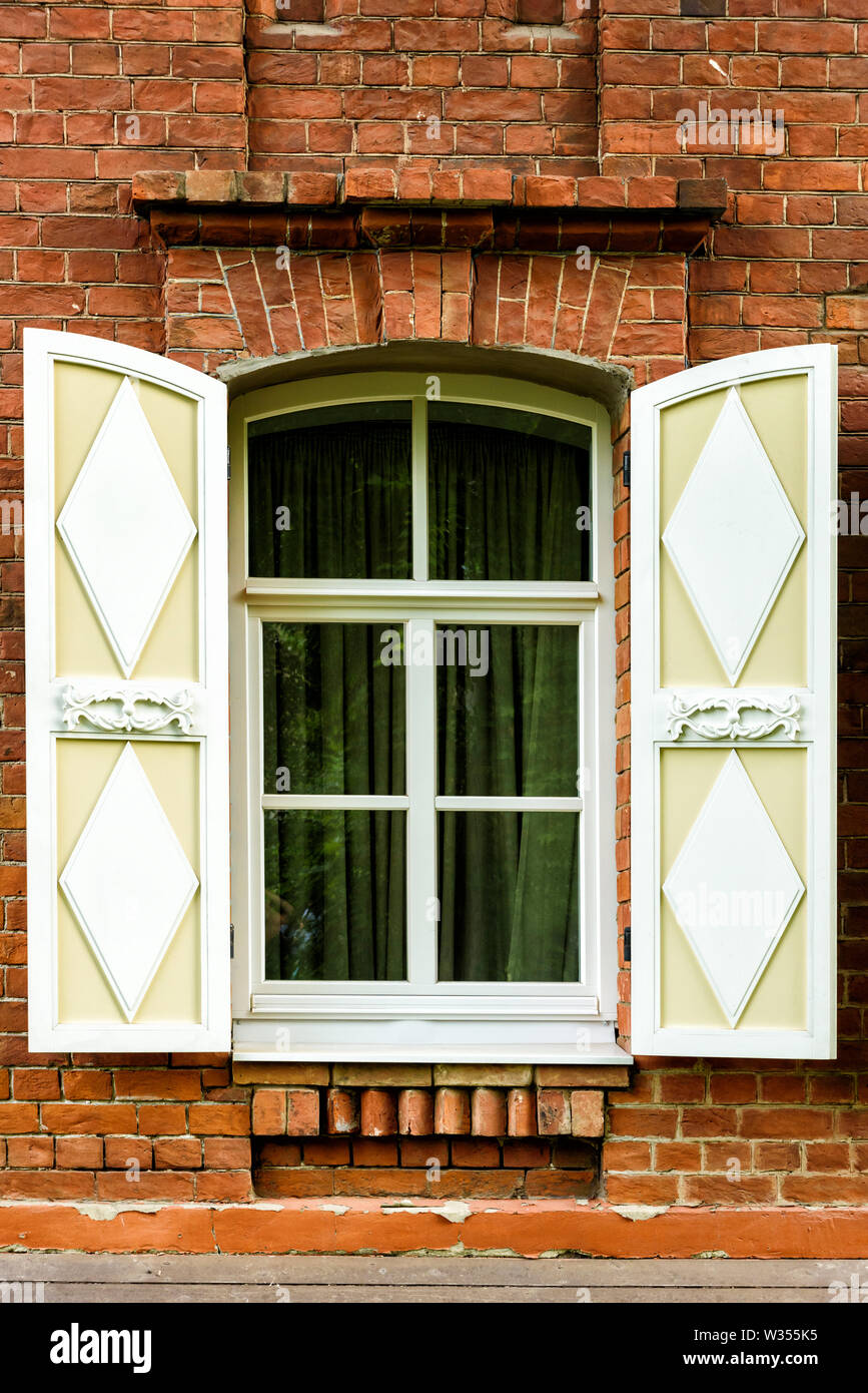 Window with the wooden carved architrave in the old wooden house in the ...