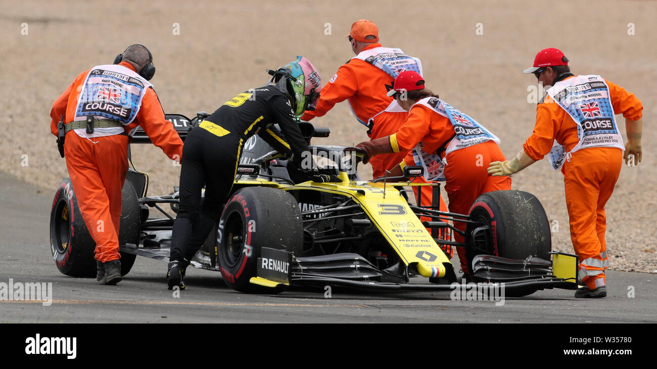 Renault driver Daniel Ricciardo helps the marshalls to push his car during practice day for the British Grand Prix at Silverstone, Towcester. Stock Photo