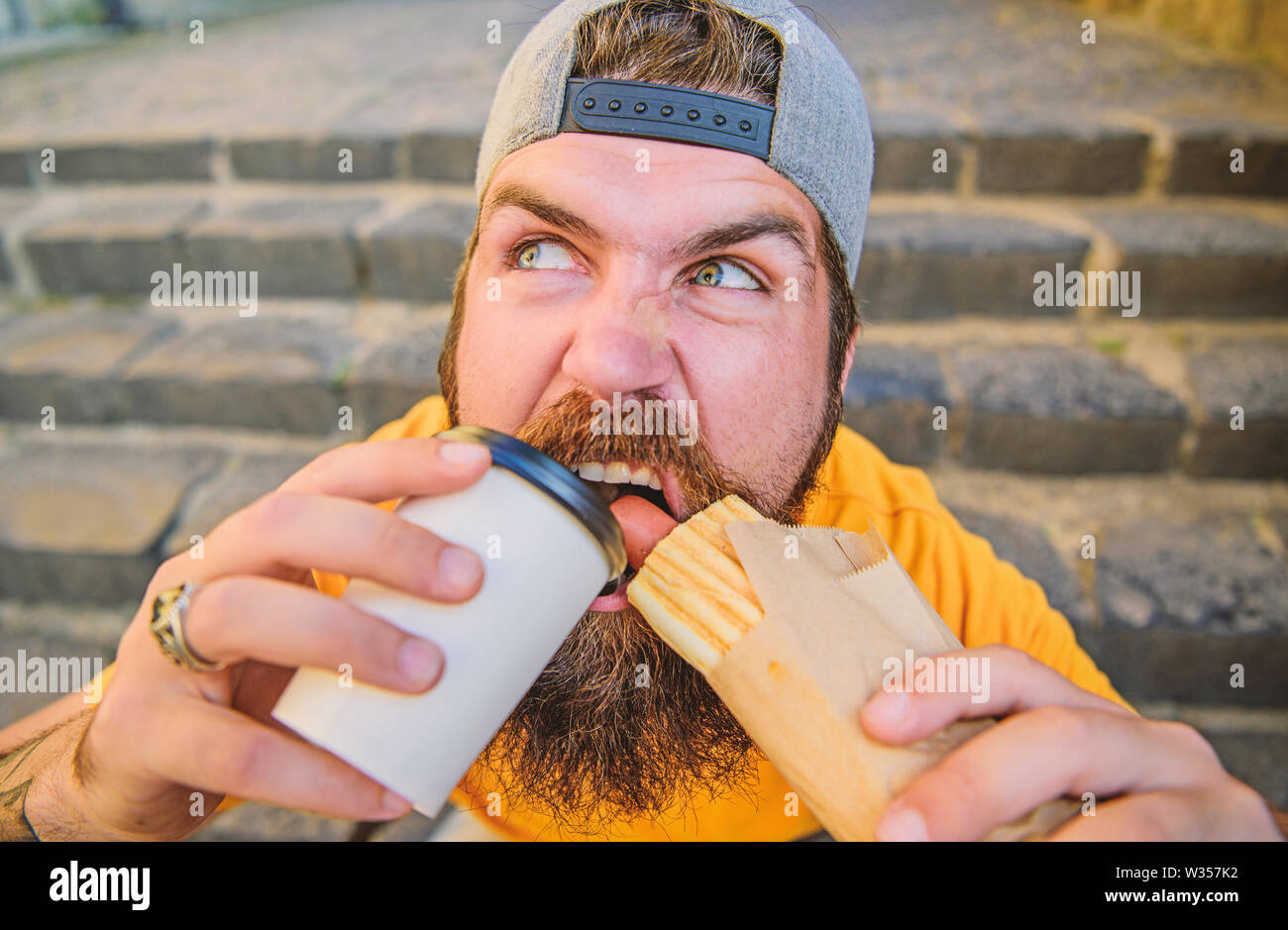 Snack for good mood. Street food concept. Man bearded eat tasty sausage ...