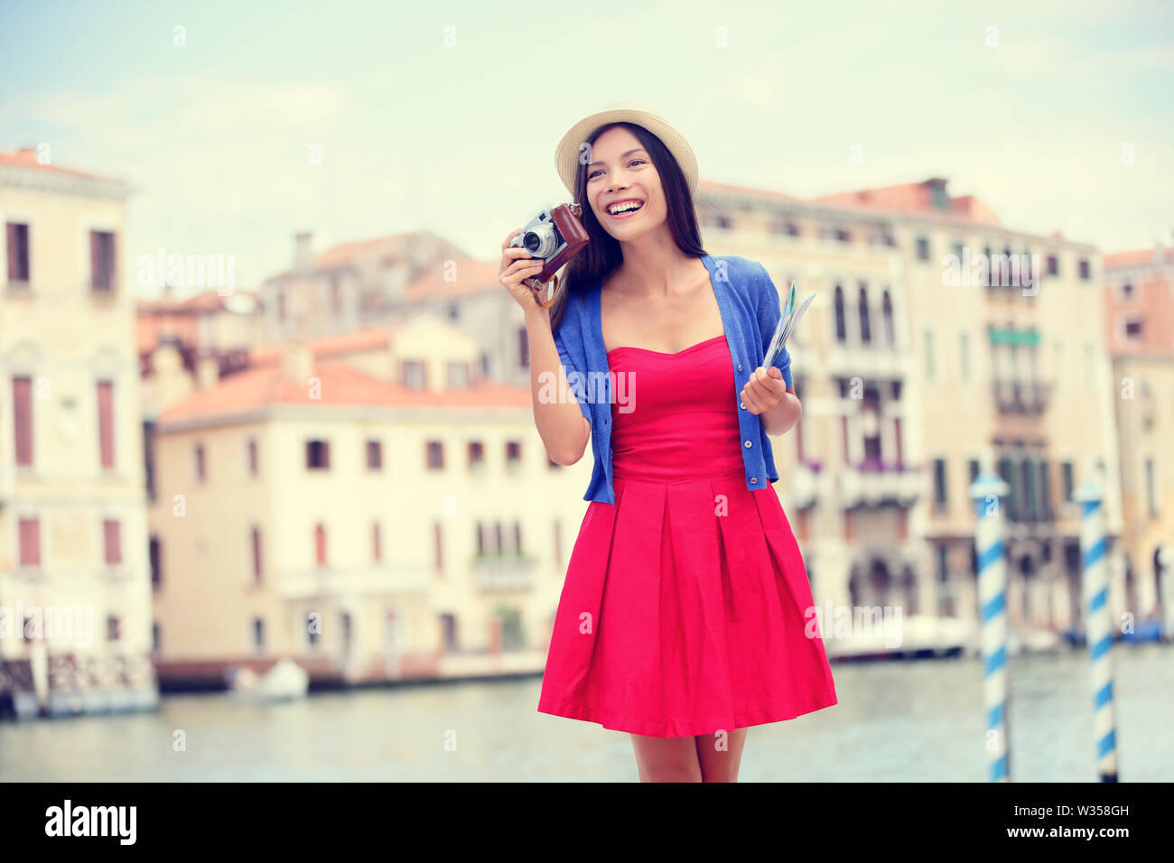 Travel tourist woman with camera and map in Venice, Italy. Vintage retro style Asian girl on vacation smiling happy by Grand Canal. Mixed race Asian Caucasian girl having fun traveling outdoors. Stock Photo