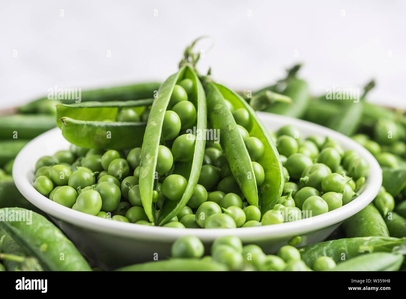 Bowl of Fresh garden peas with peas in the pod and empty pods Stock Photo