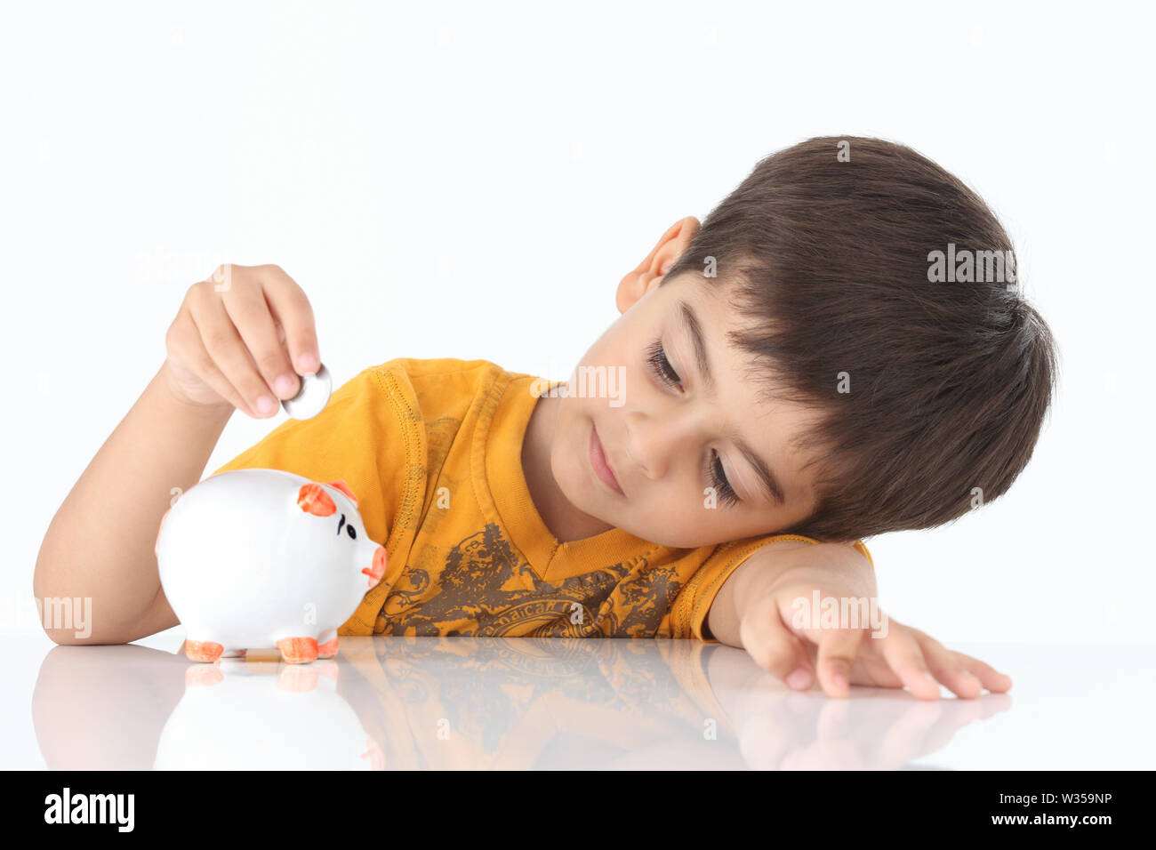 Boy inserting coin into a piggy bank Stock Photo - Alamy
