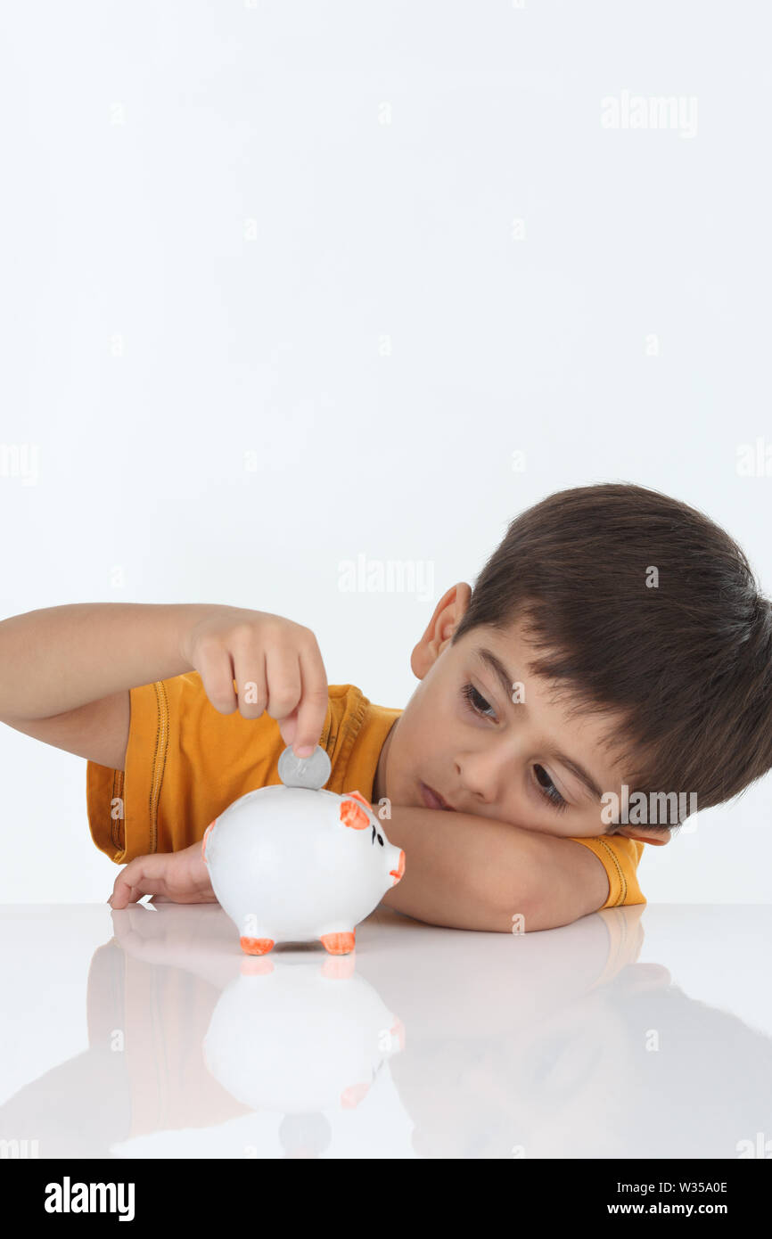 Boy inserting coin into a piggy bank Stock Photo - Alamy
