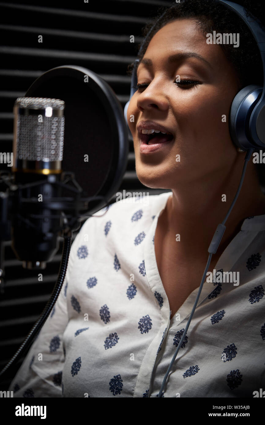 Female Vocalist Wearing Headphones Singing Into Microphone In Recording