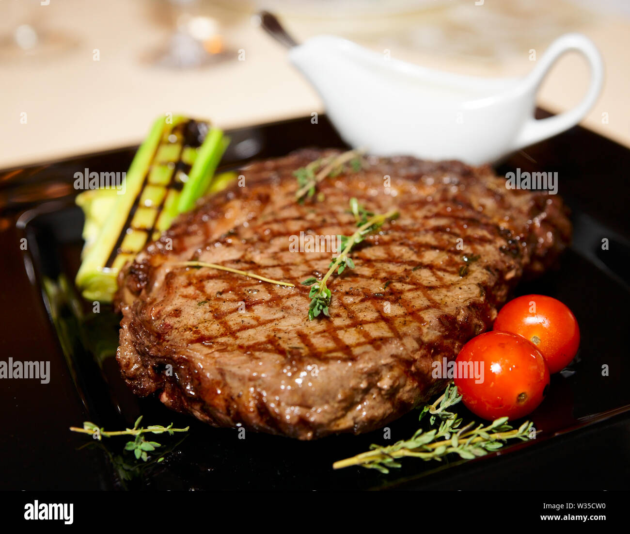 Rib Eye Steak Served On Black Plate With Sauce Herbs And Grilled Vegetables Stock Photo Alamy