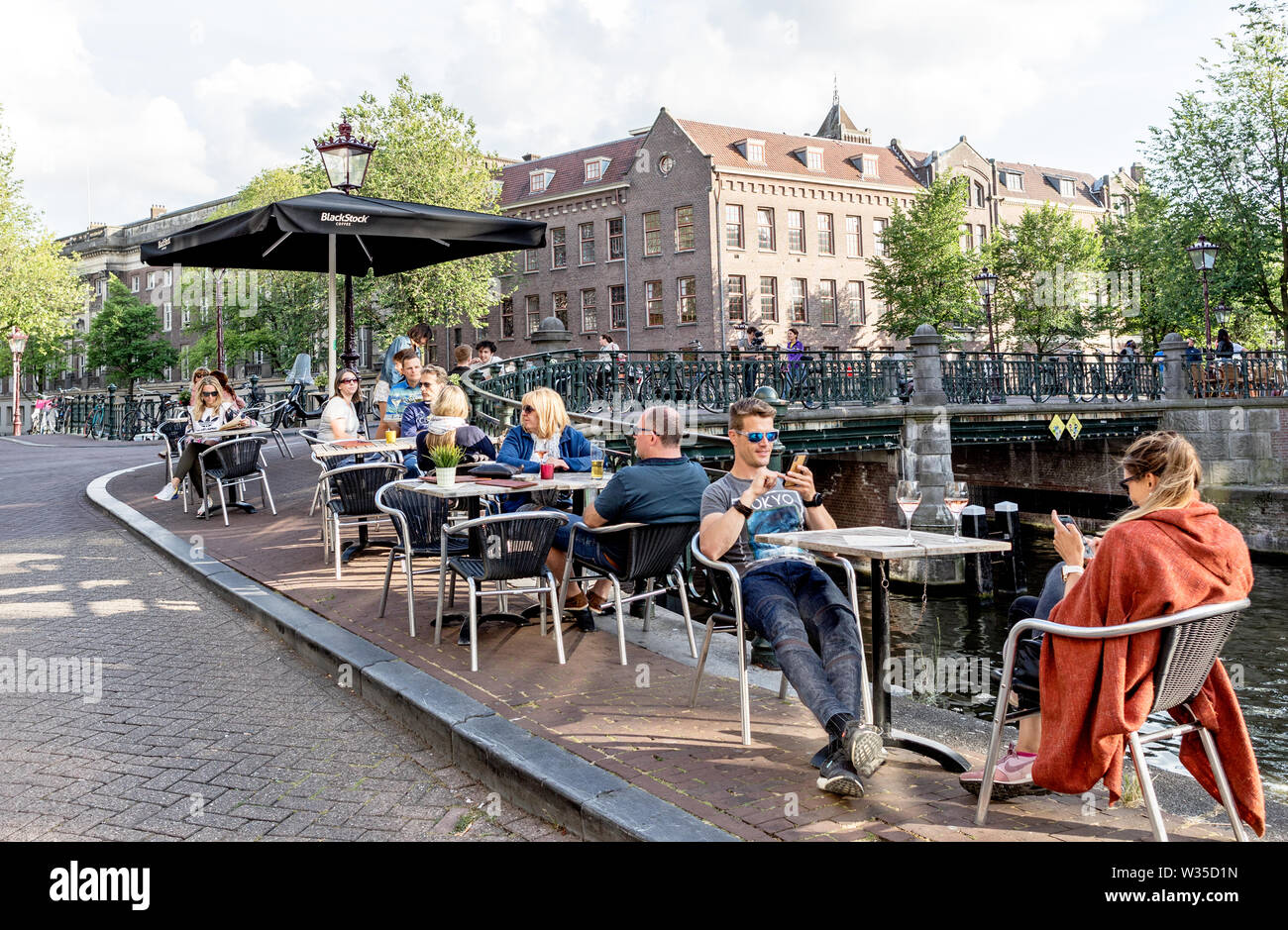 People Relaxing with Wine by  A Canal Amsterdam Holland Stock Photo