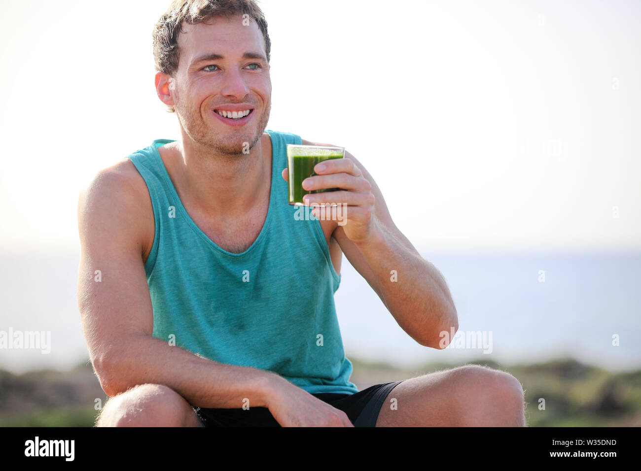 Green smoothie man drinking vegetable juice after running sport fitness