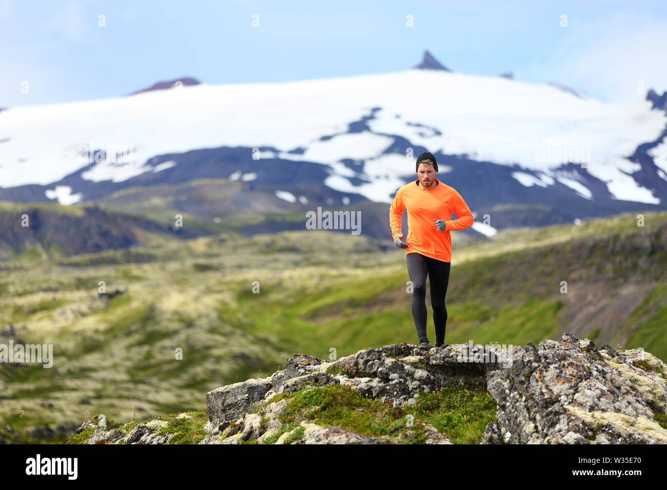 Running man exercising - trail runner athlete. Fit male sport fitness model training and jogging outdoors living healthy lifestyle in beautiful mountain nature, Snaefellsjokull, Snaefellsnes, Iceland. Stock Photo