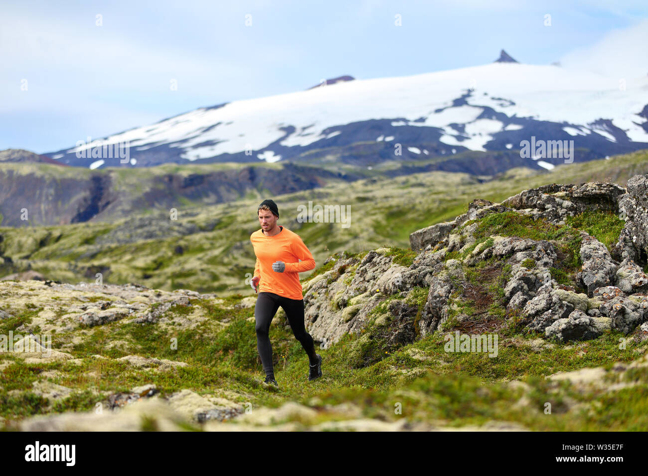 Running man athlete exercising trail runner. Fit male sport fitness model training and jogging outdoors in beautiful mountain nature landscape by Snaefellsjokull, Snaefellsnes, Iceland. Stock Photo