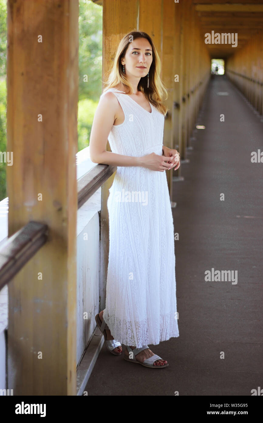 Young beautiful girl in a white dress close-up on the aqueduct bridge ...