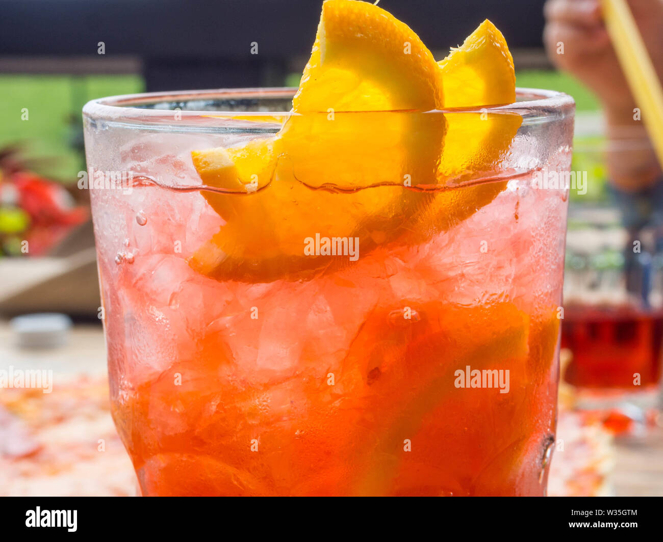 Red coctail with lemon and orange slices, and ice cubes, chilling time in bar Stock Photo
