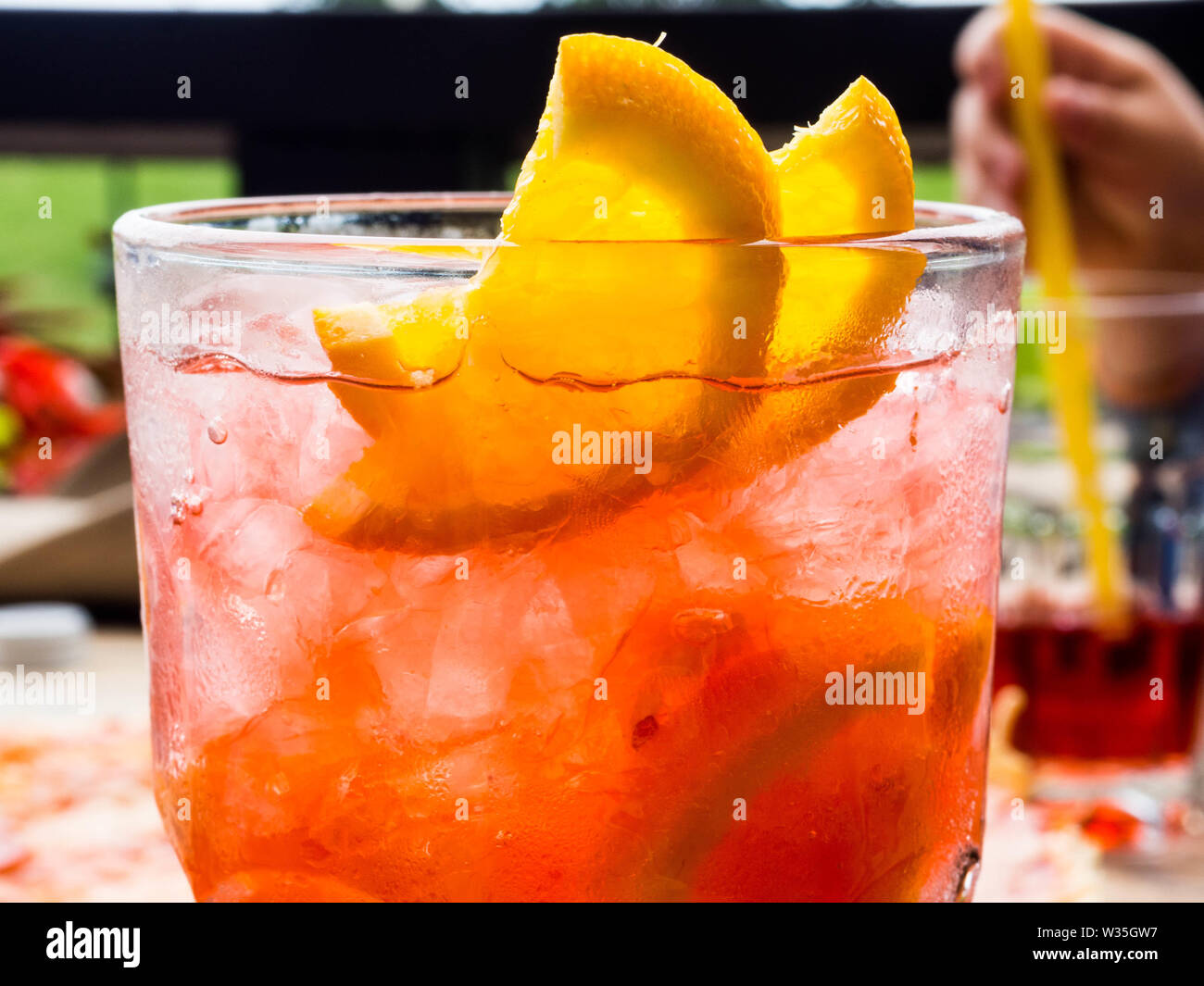 Red coctail with lemon and orange slices, and ice cubes, chilling time in bar Stock Photo