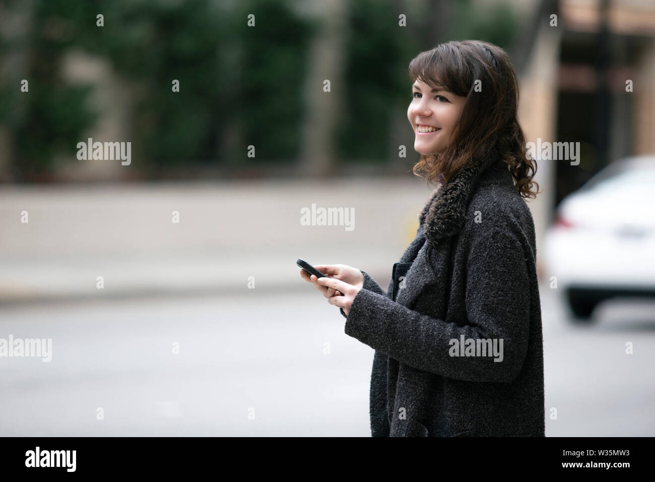 Young female using mobile phone app and waiting for a rideshare or