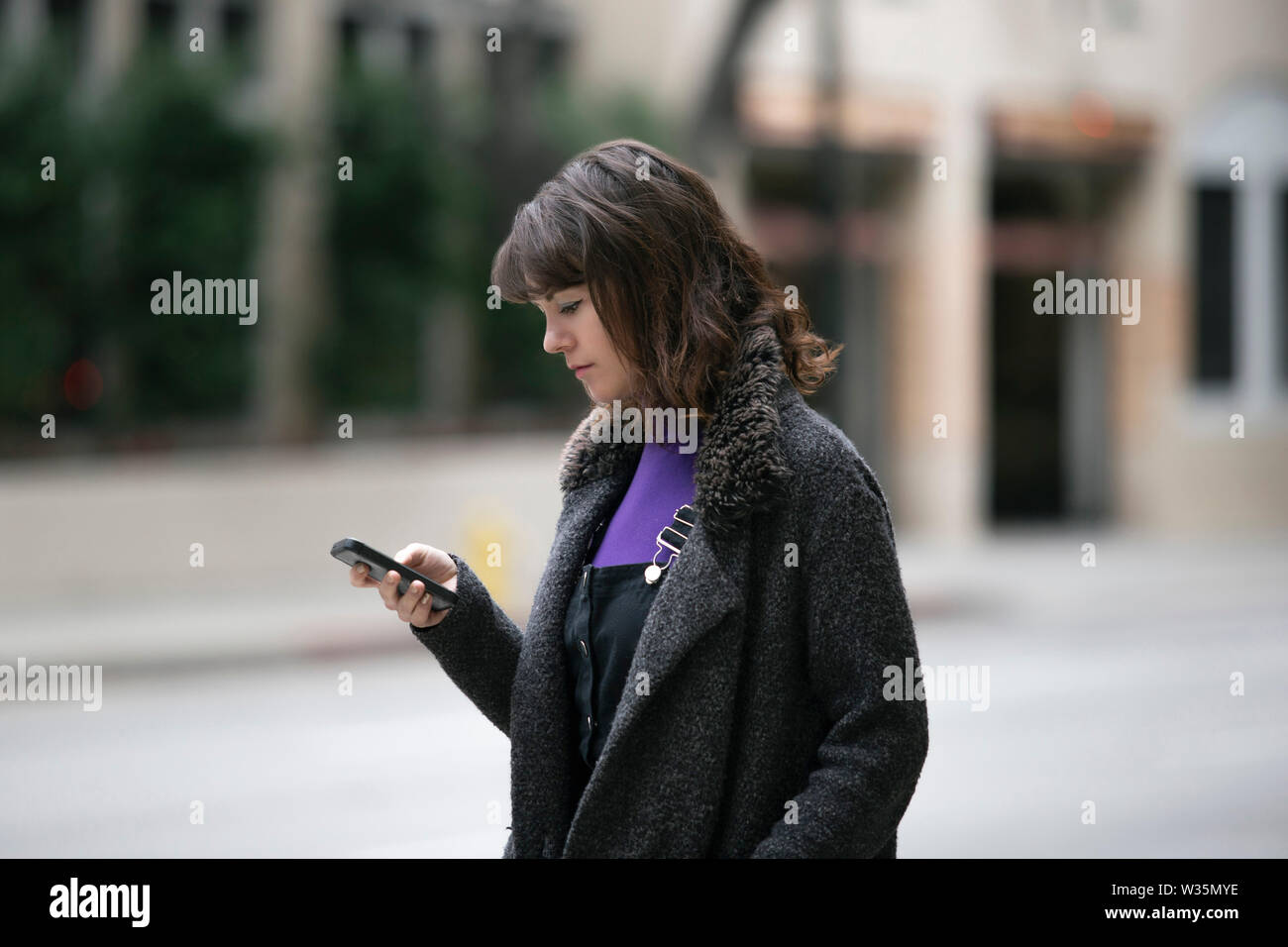 Young female using mobile phone app and waiting for a rideshare or