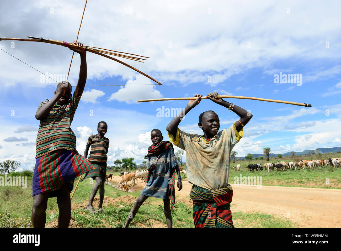UGANDA, Karamoja, young Karrimojong shepherds with bow and arrow herding cattle / junge Larimojong Hirten mit Pfeil und Bogen Stock Photo