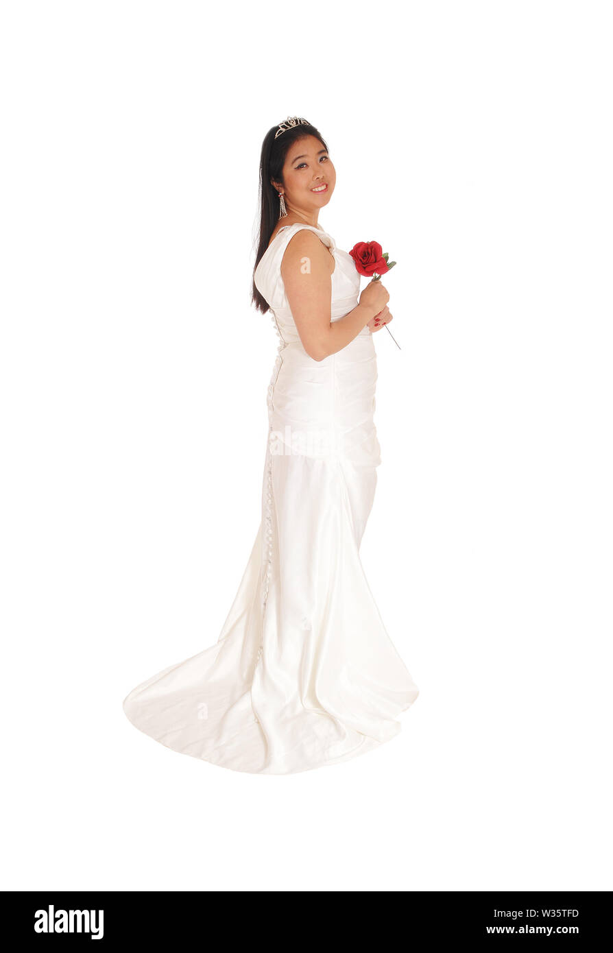 An beautiful Chinese bride, holding a red rose, standing in a white  wedding dress in profile isolated for white background Stock Photo