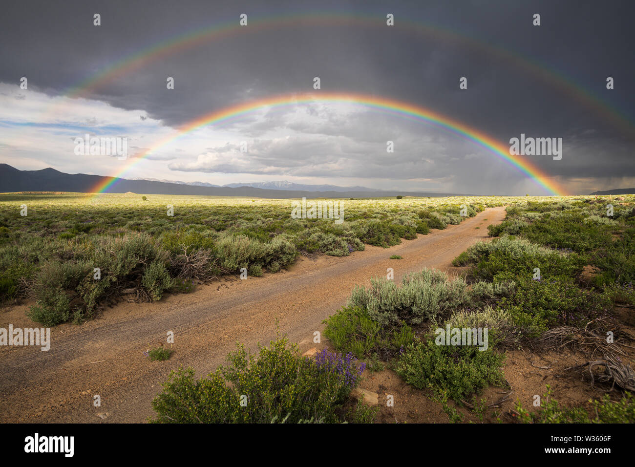 Desert double rainbow over sage brush and dirt roads Stock Photo