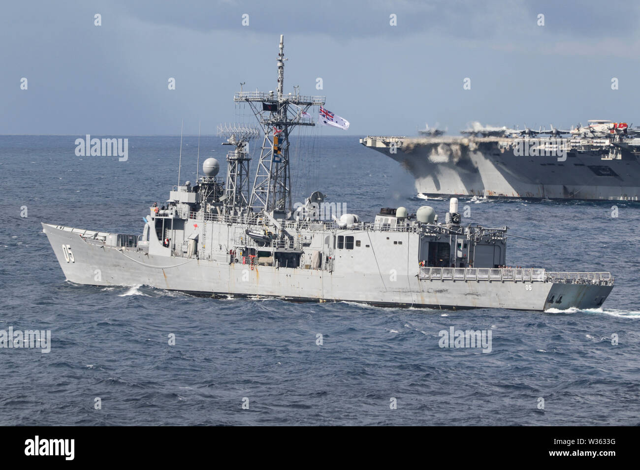 190711-N-DX072-1070 TASMAN SEA (July 11, 2019) The Royal Australian Navy Adelaide-class guided-missile frigate HMAS Melbourne (FFG 05), left, and U.S. Navy Nimitz-class aircraft carrier USS Ronald Reagan (CVN 76), transit with the amphibious transport dock ship USS Green Bay (LPD 20) in a photo exercise (PHOTOEX) during Talisman Sabre 2019. Green Bay, part of the Wasp Expeditionary Strike Group, with embarked 31st Marine Expeditionary Unit, is currently participating in Talisman Sabre 2019 off the coast of Northern Australia. A bilateral, biennial event, Talisman Sabre is designed to improve U Stock Photo