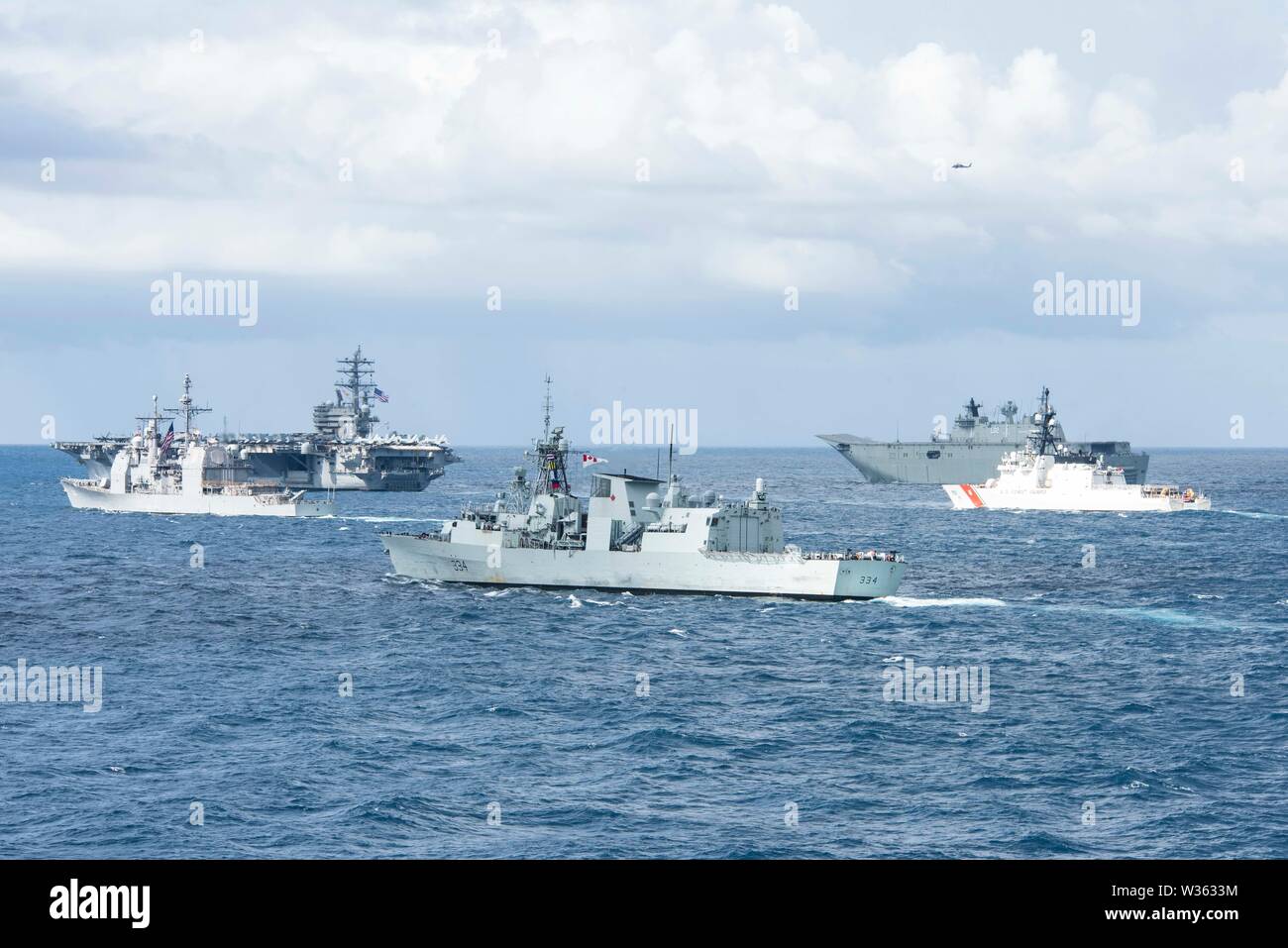 190711-N-DX072-1052 TASMAN SEA (July 11, 2019) The U.S. Navy Nimitz-class aircraft carrier USS Ronald Reagan (CVN 76), top left, the U.S. Navy Ticonderoga-class guided-missile cruiser USS Chancellorsville (CG 62), left, the Royal Canadian Navy Halifax-class frigate HMCS Regina (FFH 334), center, the Royal Australian Navy Canberra-class landing helicopter dock ship HMAS Canberra (L02), top right, and the Legend-class cutter USCGC Stratton (WMSL 752), right, transit by the amphibious transport dock ship USS Green Bay (LPD 20) in a photo exercise (PHOTOEX) during Talisman Sabre 2019. Green Bay, p Stock Photo