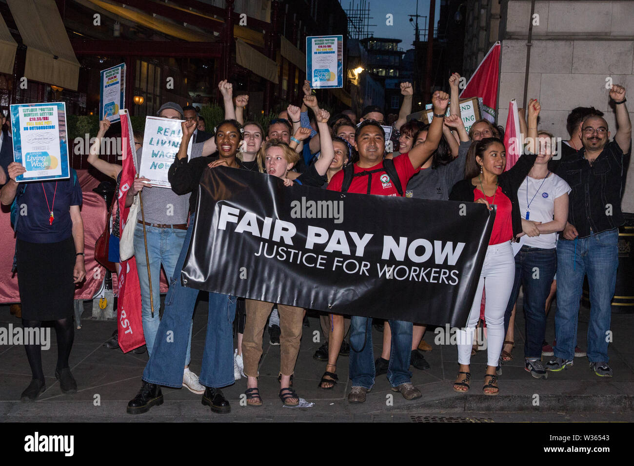 London, UK. 12 July, 2019. Members of the Cleaners and Facilities Branch of the IWGB (Independent Workers of Great Britain) trade union protest outside 5 Hertford Street in Mayfair, which also houses exclusive private club Loulou’s, to call for its kitchen porters, recently outsourced through ACT, to be paid the London Living Wage and given terms and conditions including suitable sick pay, holidays and pension contributions. Numerous unmarked security guards were present outside the venue. Credit: Mark Kerrison/Alamy Live News Stock Photo