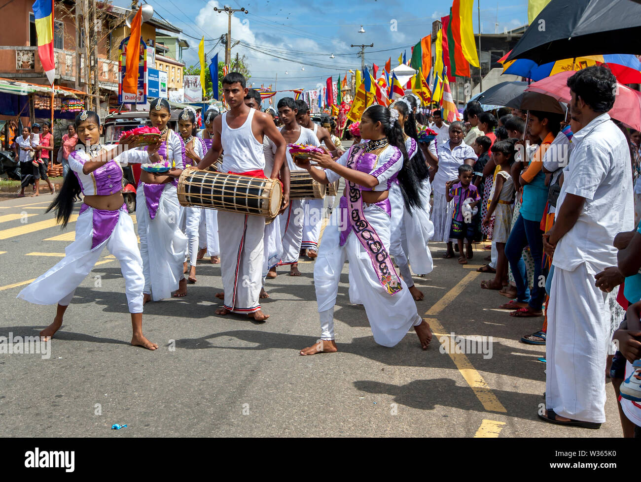 HIKKADUWA, SRI LANKA - SEPTEMBER 08, 2013 : Sri Lankan girls dance to the beat of Yak Beraya drums along the coastal road during the Buddhist perahera Stock Photo